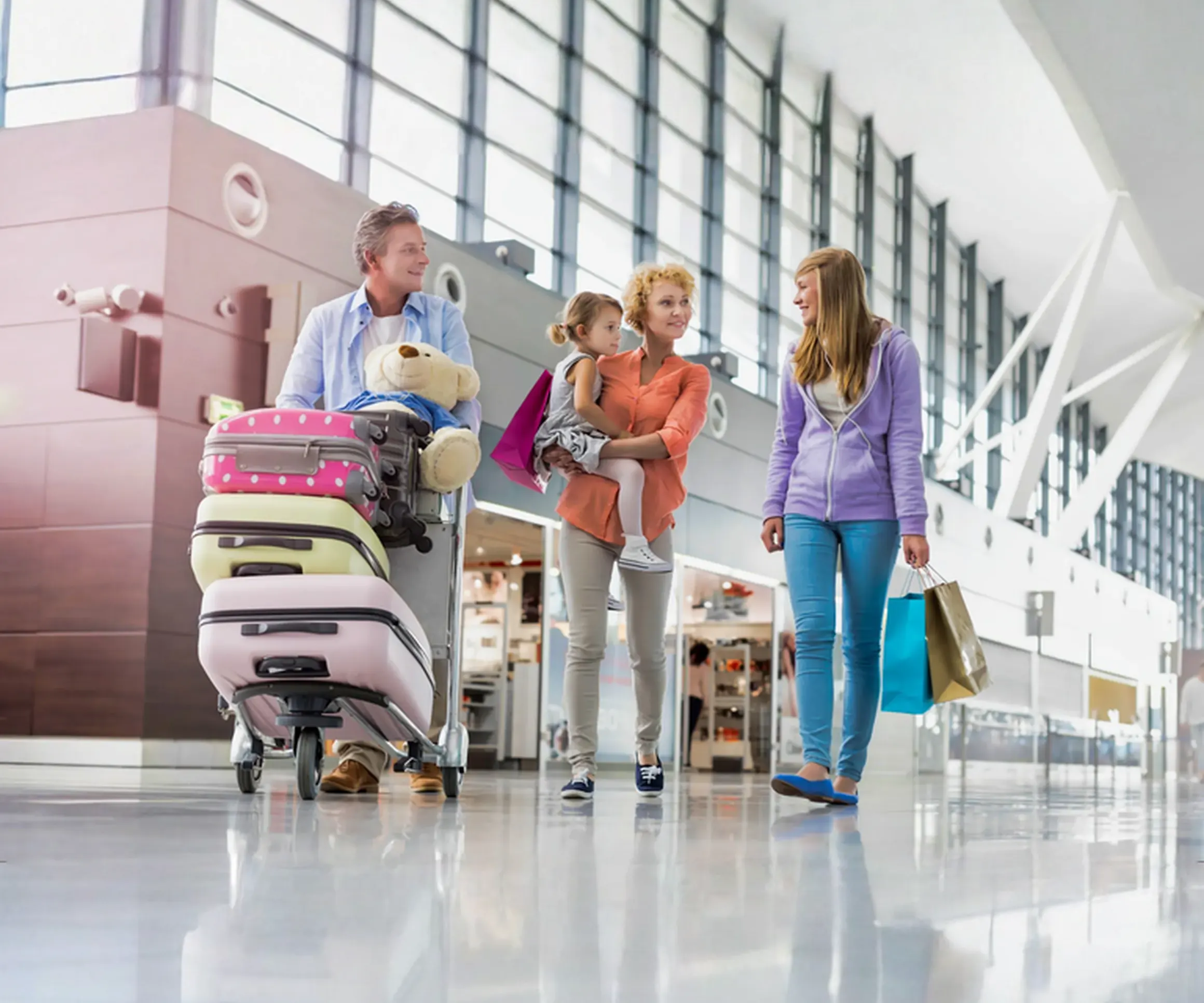Family with a luggage cart walking through a bright airport terminal
