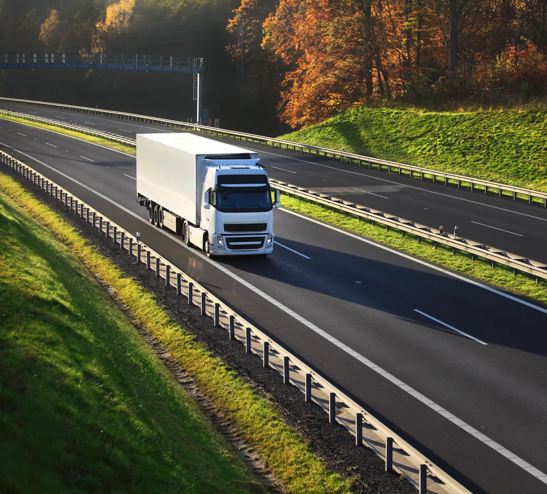 White truck on a quiet highway through autumn countryside